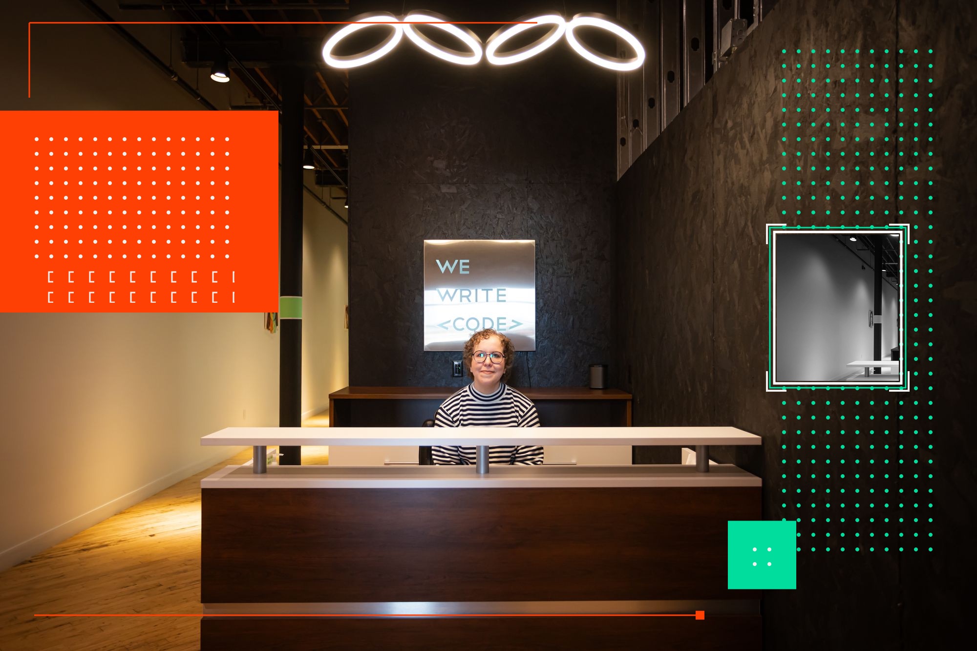 The We Write Code reception desk beneath ring lights, with the WE WRITE CODE sign behind it
